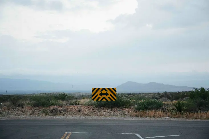 a yellow and black sign sitting on the side of a road